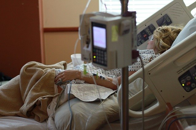 Frau im Krankenhausbett umgeben von Geräten und Schläuchen